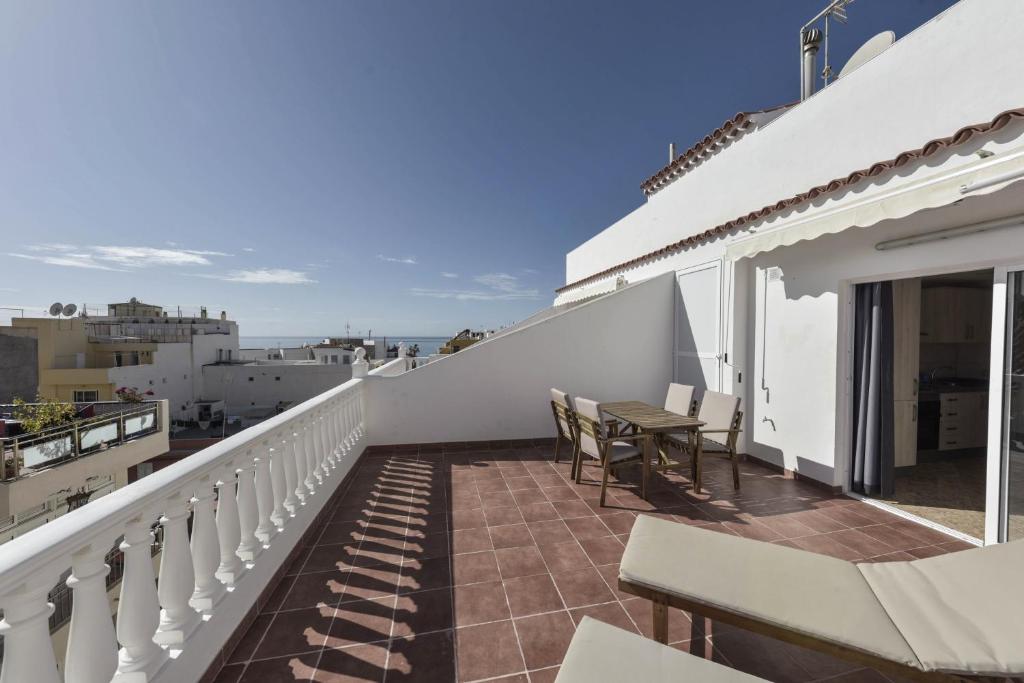 a balcony with a table and chairs on a building at Apartamento Pardela in Playa de San Juan