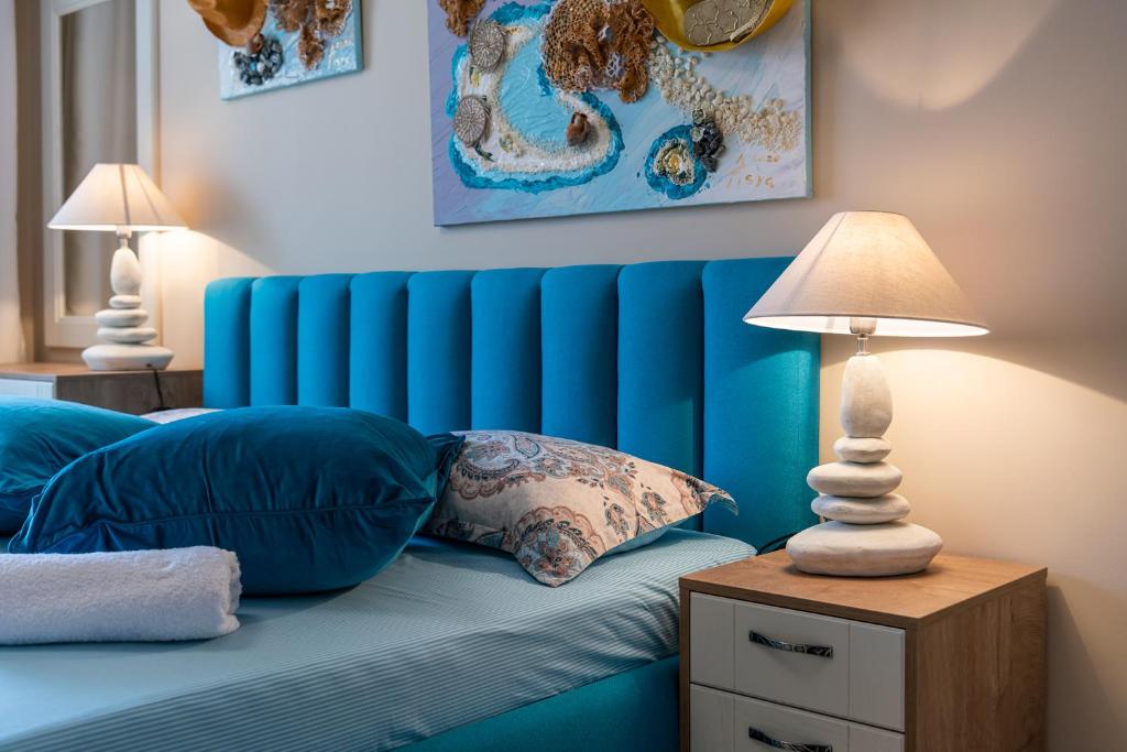 a blue bed with a blue headboard and two lamps at Aquamarine in Pomorie
