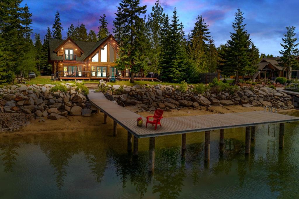 a red chair sitting on a dock in front of a house at Antler Cove Log Home in Sagle