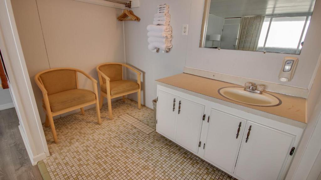 a bathroom with a sink and a mirror and two chairs at Rideau Oceanfront Motel in Ocean City