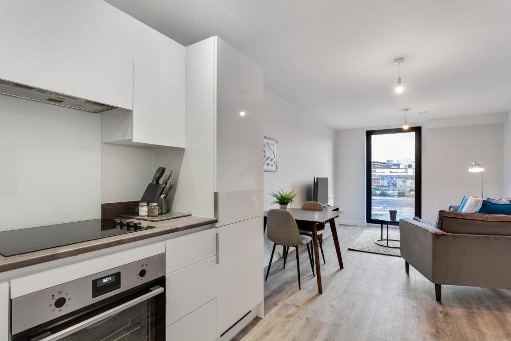 a kitchen with white cabinets and a dining room at Stylish 1 bed flat in Central Birmingham in Birmingham