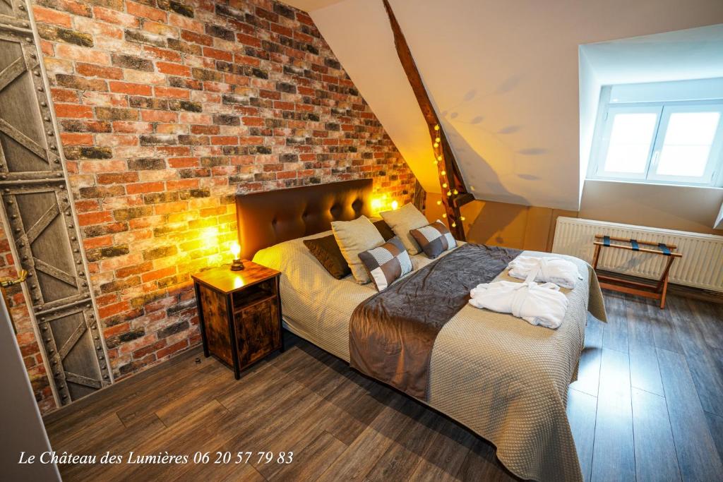 een slaapkamer met een bed en een bakstenen muur bij Le Château des Lumières de la Baie de Somme in Saint-Blimont