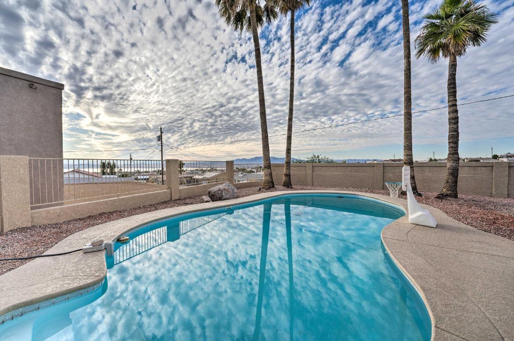 une piscine avec des palmiers et un ciel nuageux dans l'établissement Upgraded Lake Havasu Oasis with Pool and Views!, à Lake Havasu City