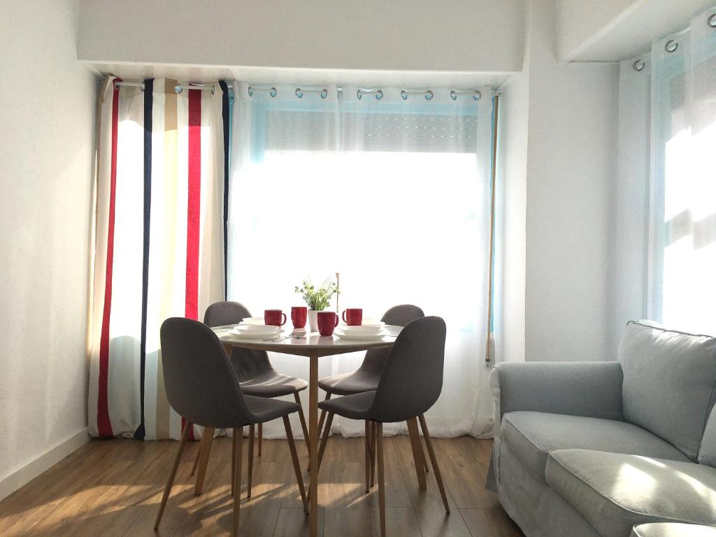 a living room with a table and chairs and a couch at Mar y Arena - 5 minutos a la playa y al centro in Santa Pola