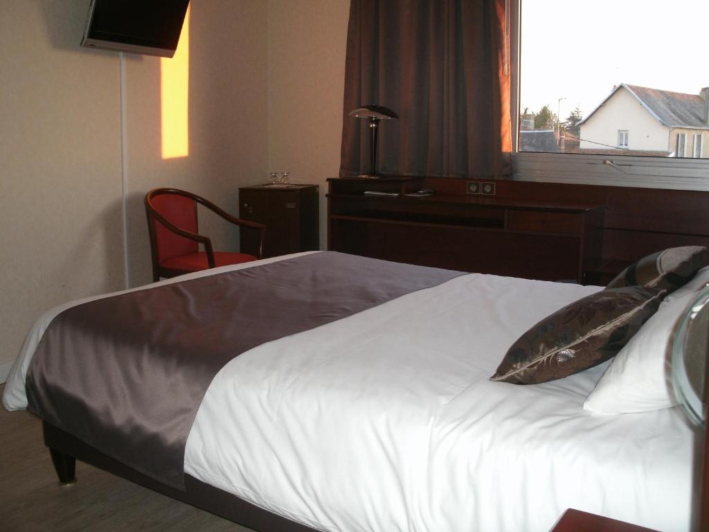 a bedroom with a bed with a desk and a window at Cit&#39;Hotel Saint Jacques in Parthenay