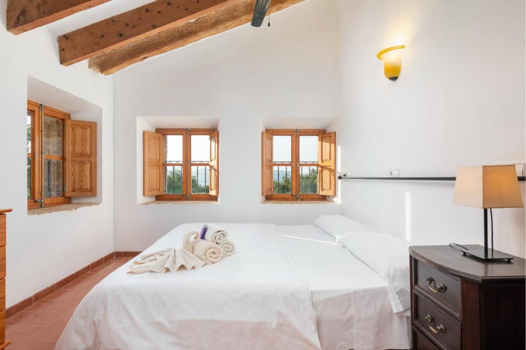 a white bedroom with a white bed and windows at Petit Hotel Hostatgeria La Victoria in Alcudia