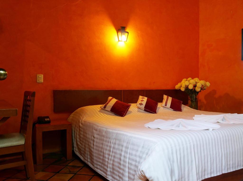 a bedroom with a large white bed with an orange wall at Hotel Posada El Paraíso in San Cristóbal de Las Casas