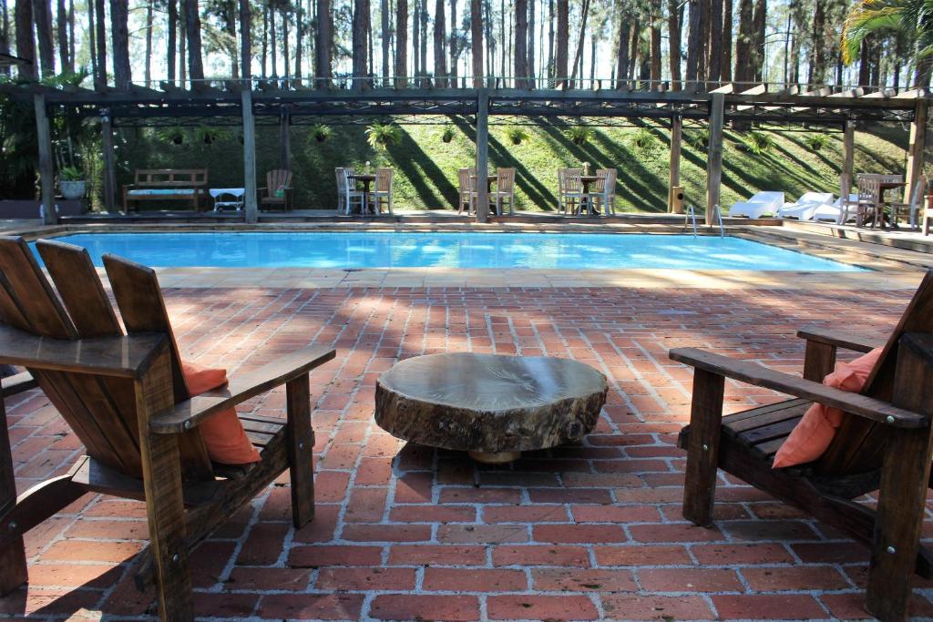 a pool with two chairs and a table and a stump at Espaço Vila Lara in São Roque