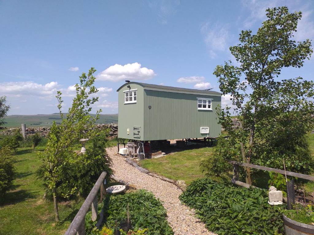 a green house sitting on top of a field at The Buteland Stop Rosie off grid Shepherds Hut in Bellingham