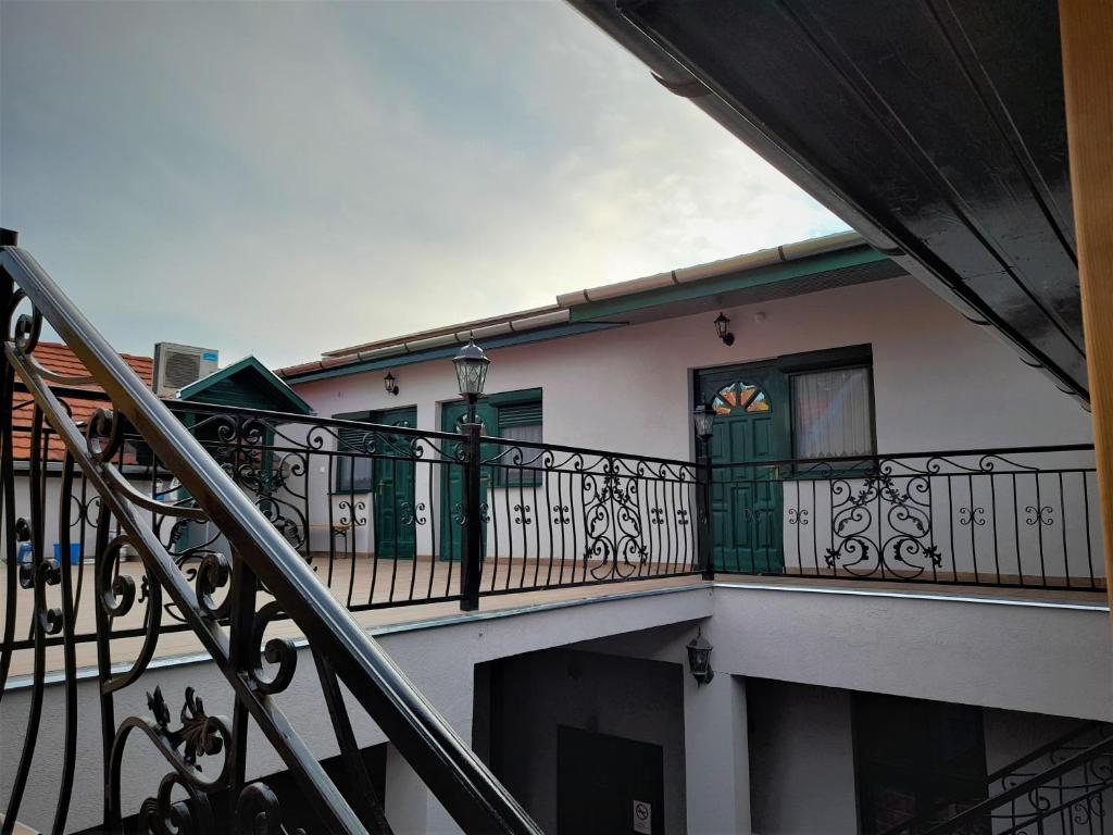 a building with a balcony with green doors at Bársony Vendéglő és Panzió in Szécsény