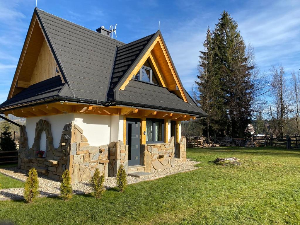 a small house with a black roof at Domek Góralski Nad Potokiem in Witów