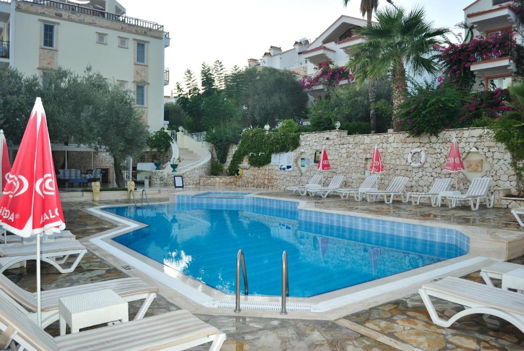 a swimming pool in a resort with chairs and umbrellas at Hotel Dionysia in Kalkan