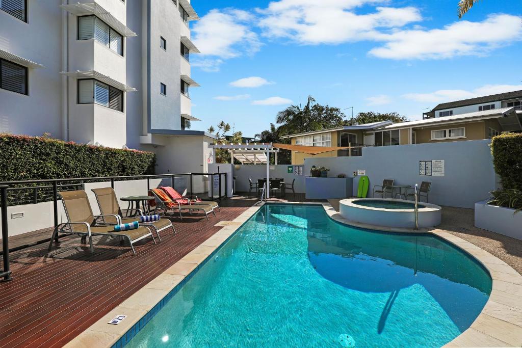 una piscina en una terraza con sillas y un edificio en Mariners Resort Kings Beach en Caloundra