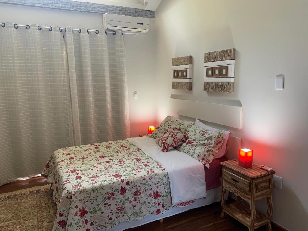um quarto com uma cama e duas velas sobre uma mesa em Chalé aconchegante para família no Centro em Penedo