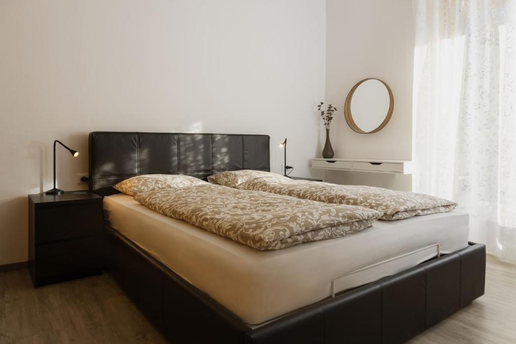 a bedroom with a bed with a black headboard and a mirror at Nina • Parchi e Fiume in Bressanone