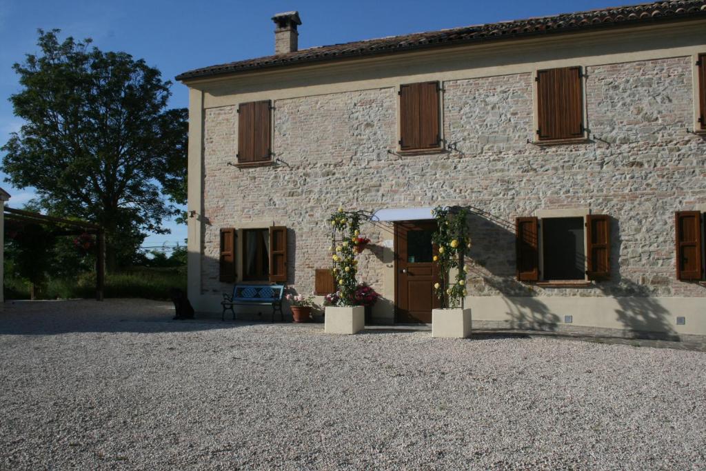 un edificio de piedra con una puerta y flores. en B&B La Fenice, en Montegridolfo