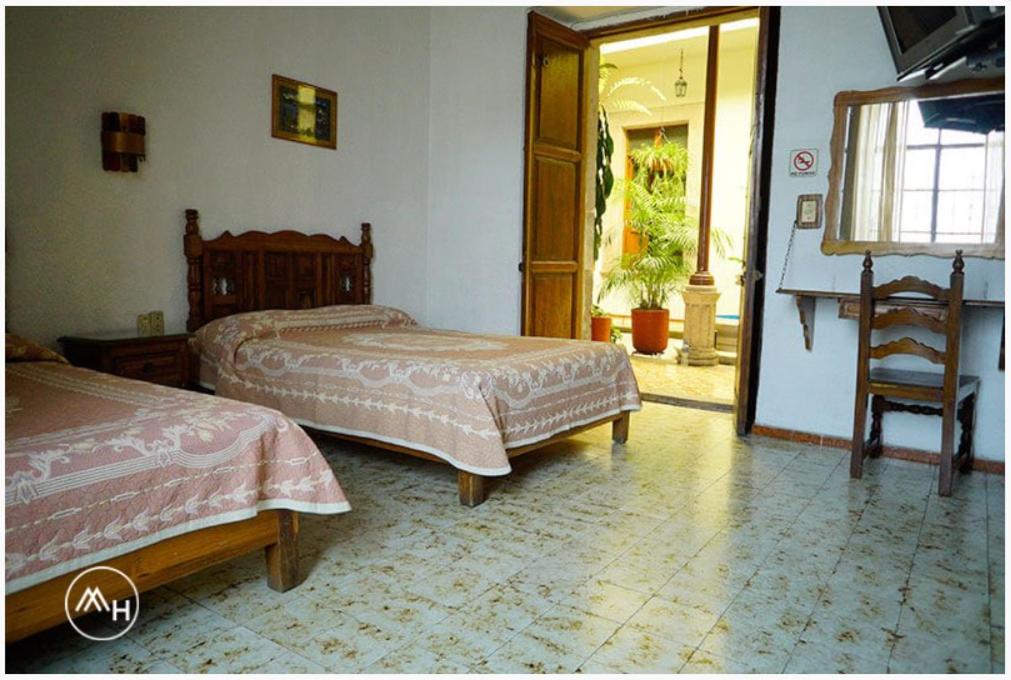 1 dormitorio con 2 camas, silla y puerta en Hotel Atilanos en Morelia