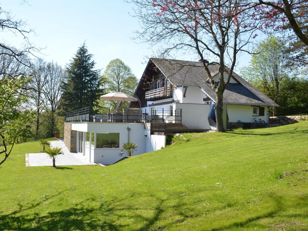 ストゥモンにあるStately Chalet in Stoumont with Pool Saunaの緑の庭のある丘の上の家