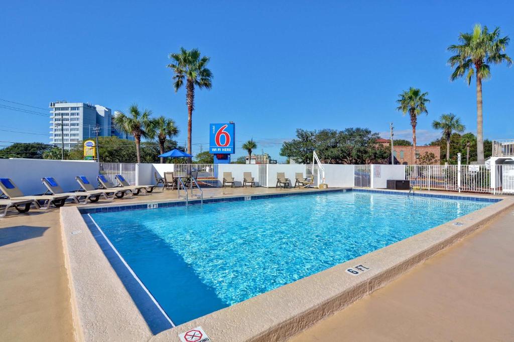 una piscina en un hotel con sillas y palmeras en Motel 6-Destin, FL, en Destin