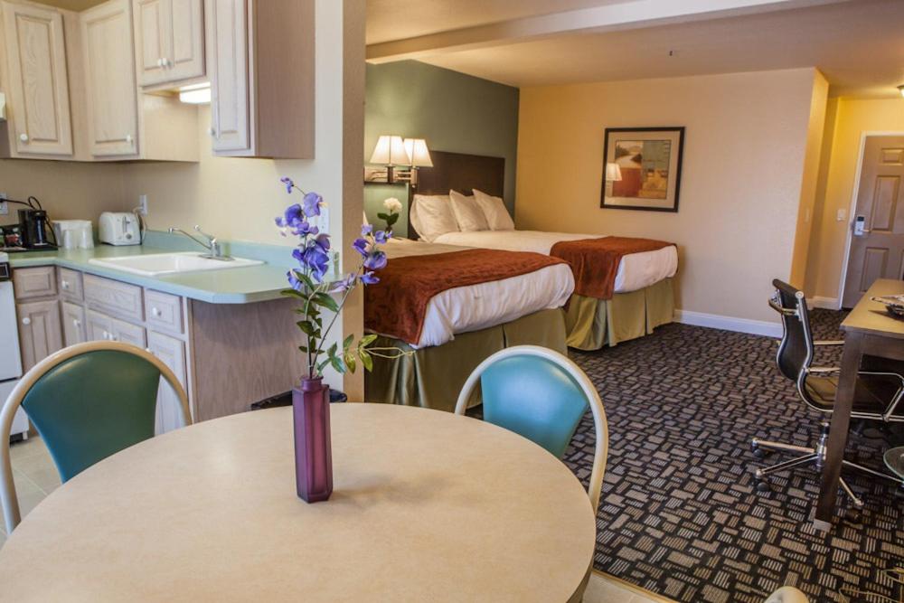 a hotel room with two beds and a table with a kitchen at Marinwood Inn & Suites in Novato