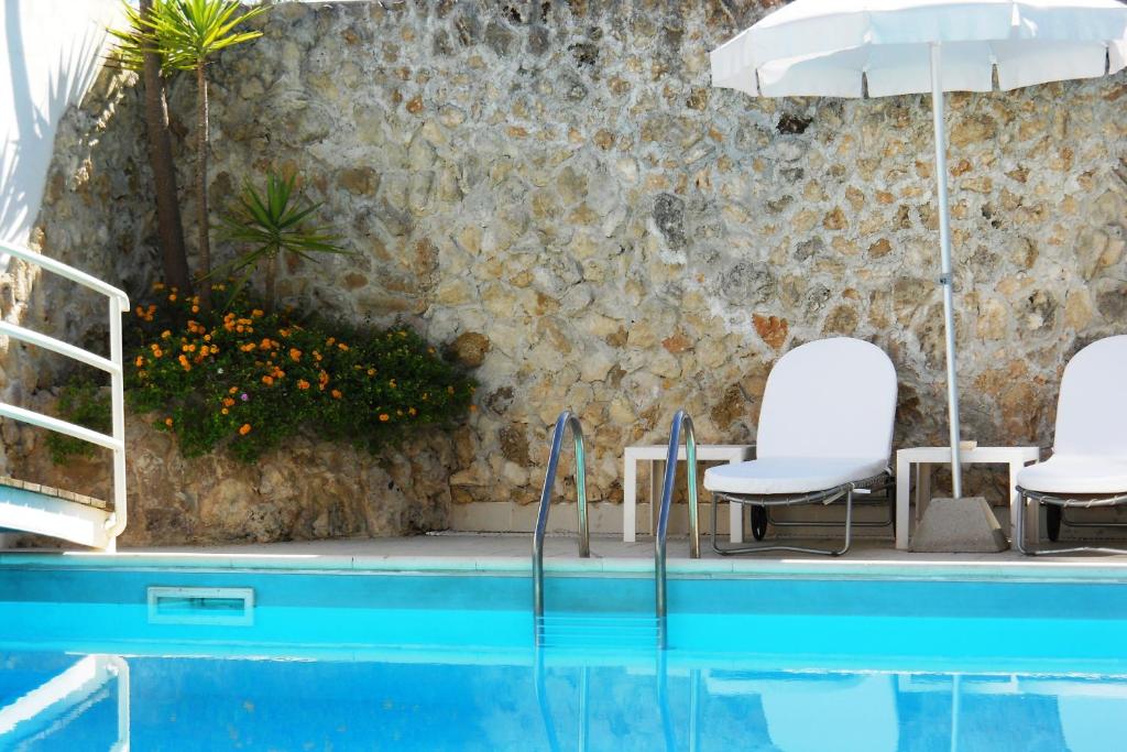 una piscina con 2 sillas y una sombrilla en Hotel Degli Haethey, en Otranto