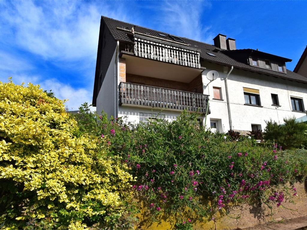 a white building with a balcony and some flowers at Quaint Apartment in Gro almerode near the Forest in Großalmerode