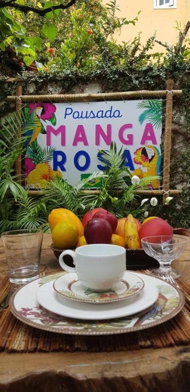 a table with a plate of fruit and a cup of coffee at Pousada Manga Rosa in Paraty