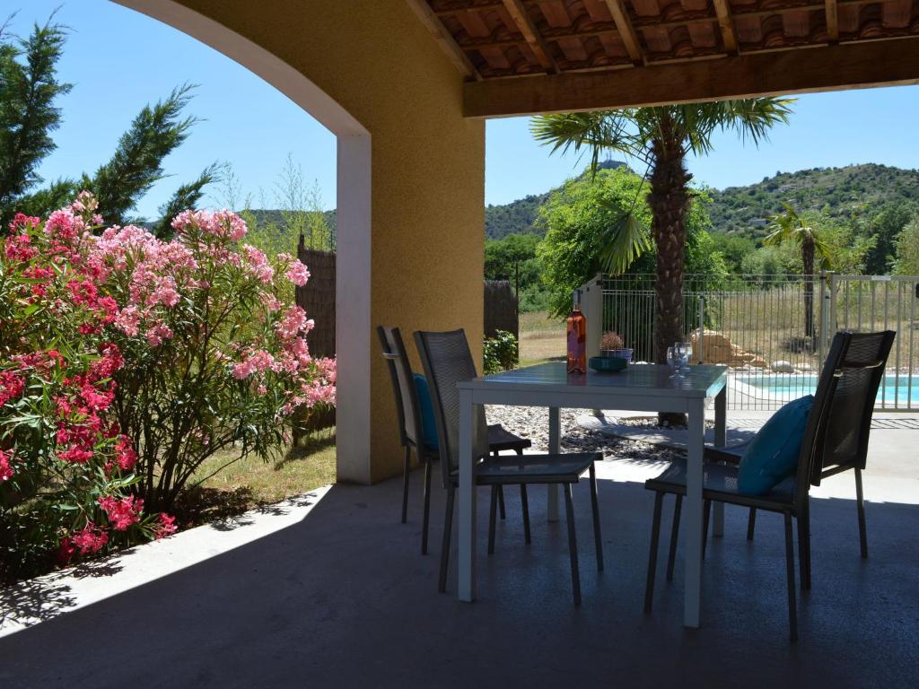 a table and chairs on a patio with flowers at Charming villa with private pool near the Ard che river in Auriolles