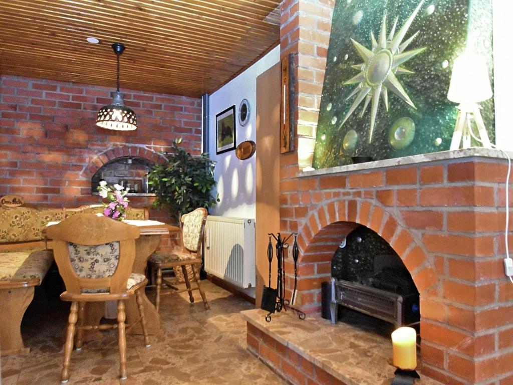 ein Zimmer mit einem gemauerten Kamin mit einem Tisch und einem Esszimmer in der Unterkunft Pleasant apartment in Thuringian Forest with garden in Kurort Steinbach-Hallenberg