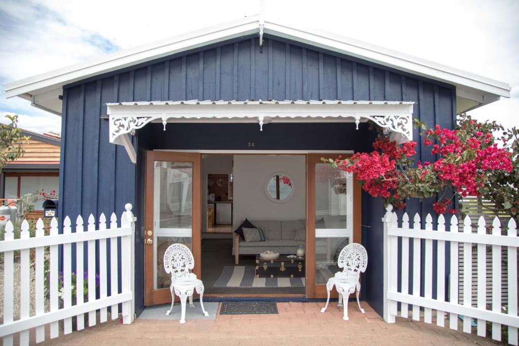 a blue house with two chairs and a fence at Beach Folly - Whitianga in Whitianga