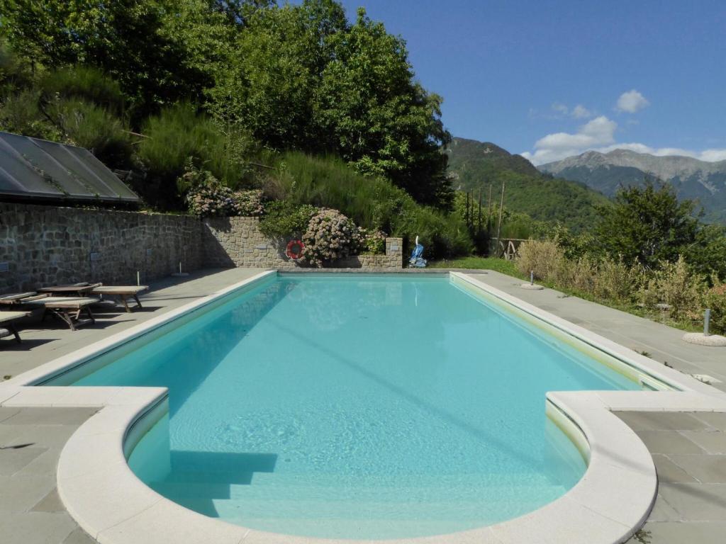 a blue swimming pool with a table and mountains in the background at Belvilla by OYO Chalet Appennino in Cutigliano