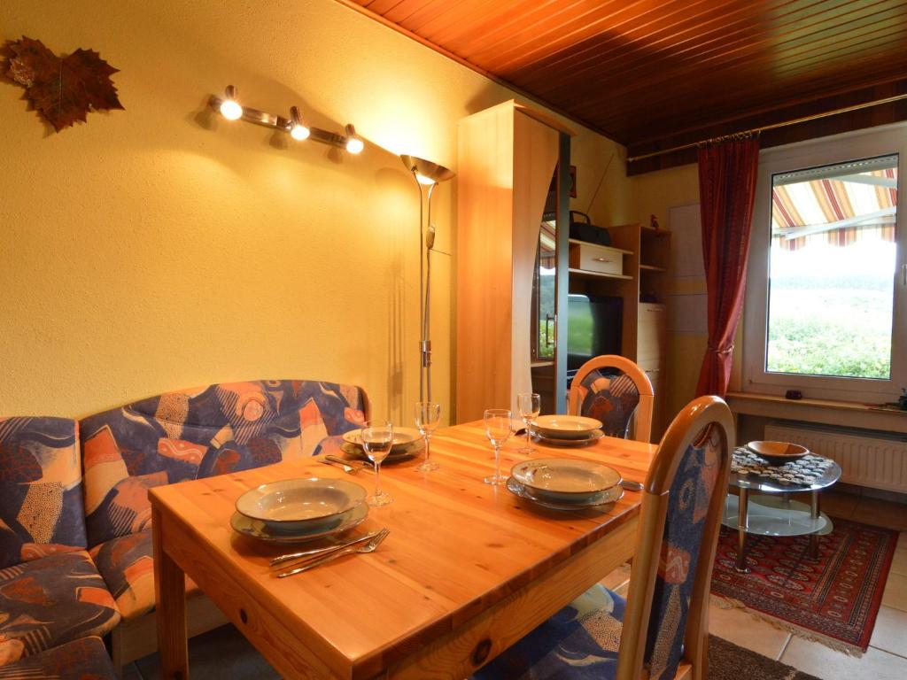 a wooden table with plates and glasses on it at Cozy Holiday Home in Boevange Clervaux with Garden in Boevange-Clervaux