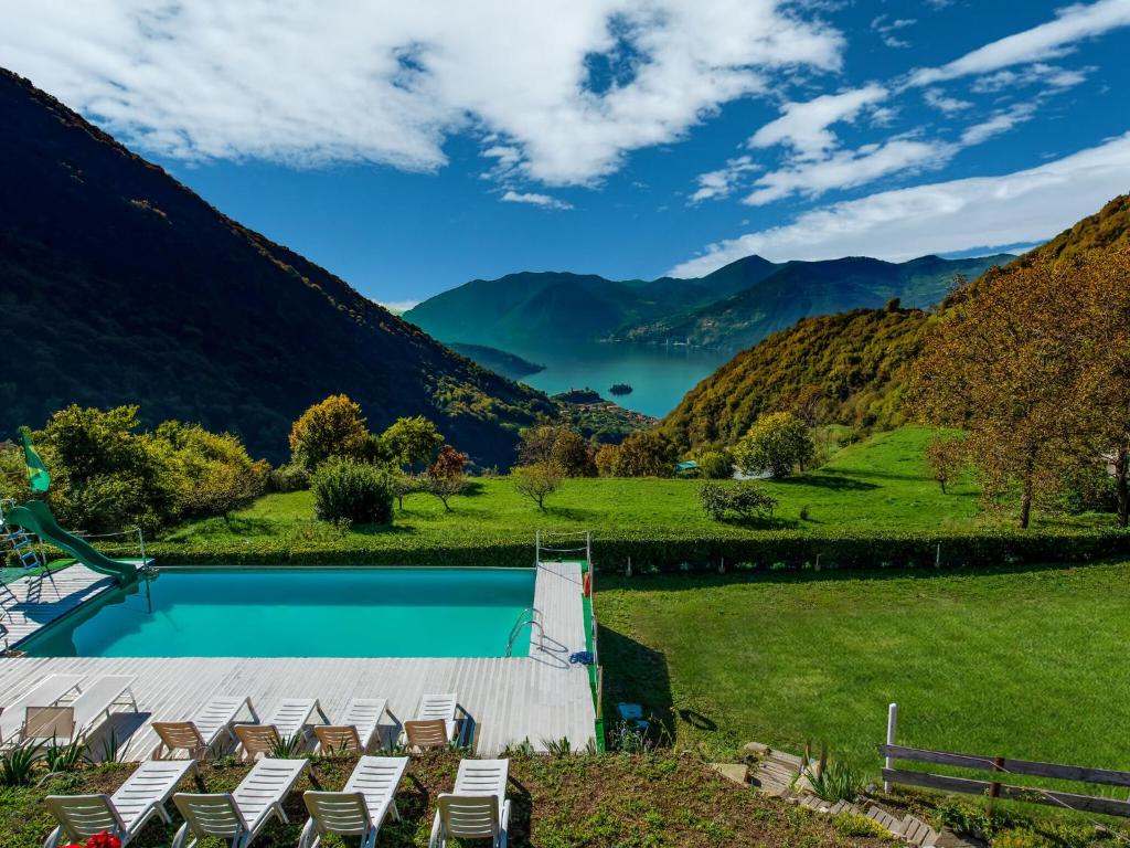 una piscina con sedie e montagne sullo sfondo di In a green and relaxing atmosphere with pool and stunning lake view a Marone