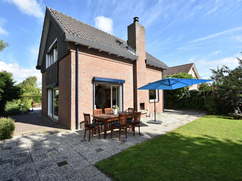 ブライニッセにあるHoliday home in Zeeland with wide viewsのパティオ(テーブル、青い傘付)