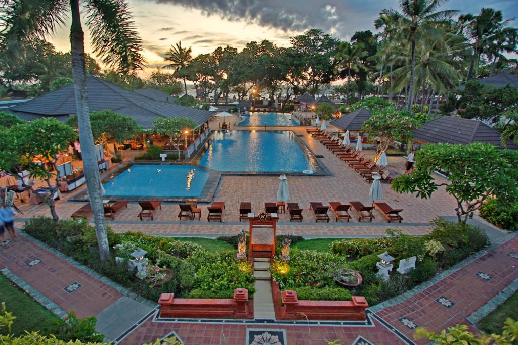 a resort with two pools with tables and chairs at The Jayakarta Bali Beach Resort in Legian
