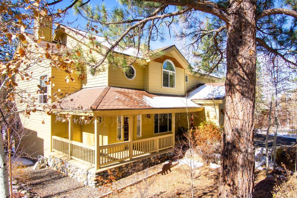 une maison jaune avec une véranda et un arbre dans l'établissement Skidder Trail Family Lodge home, à Truckee