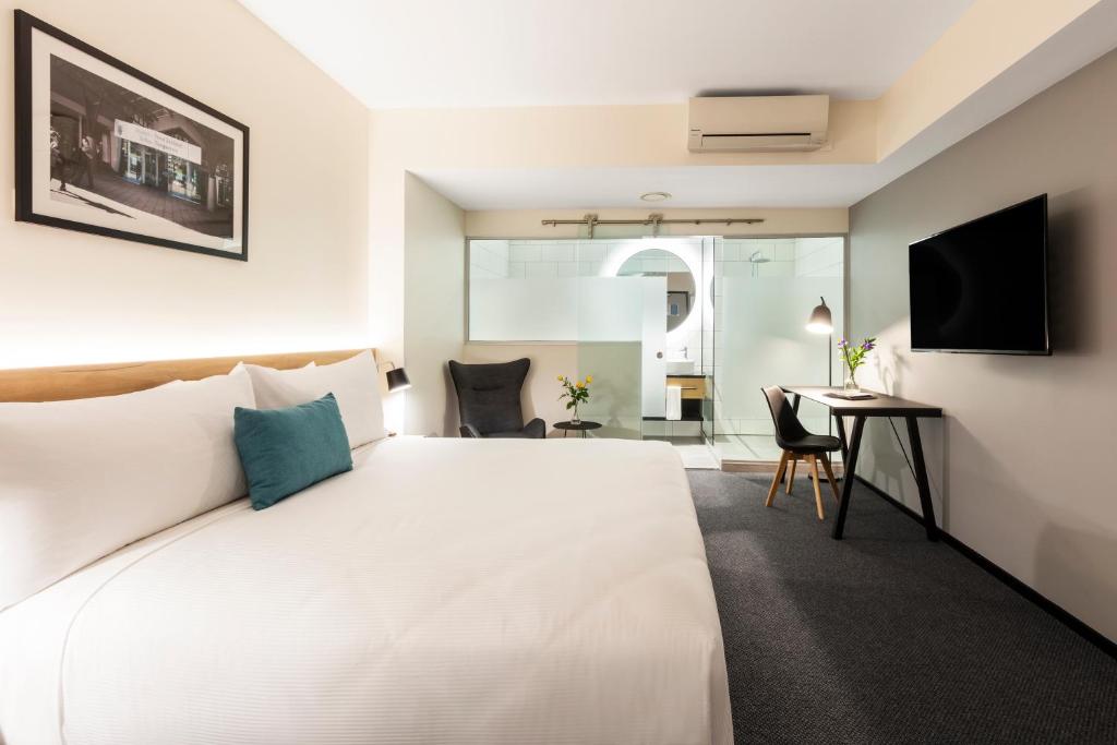 a bedroom with a large white bed and a desk at Hotel Room @ 89 Courtenay Place in Wellington