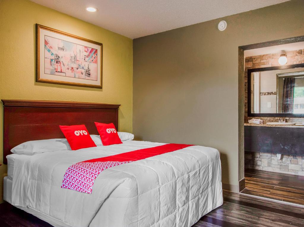 OYO Superior Budget Inn Bartow في بارتو: غرفة نوم بسرير كبير عليها وسائد حمراء