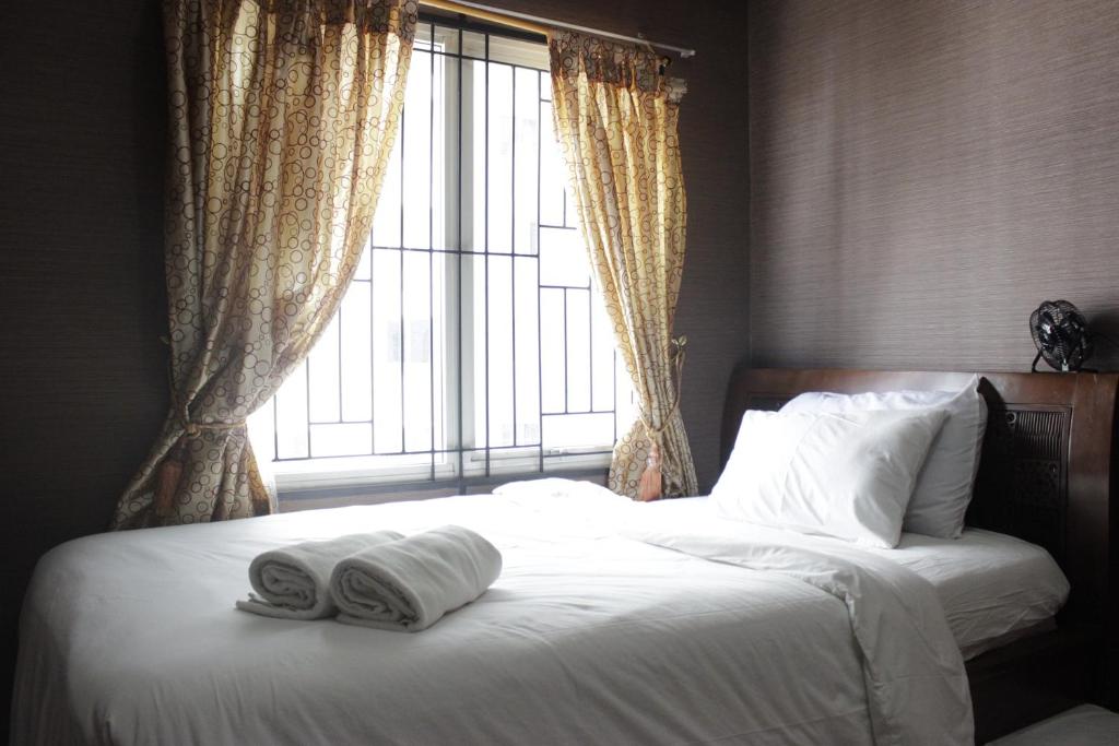 a bed with two towels on it with a window at Chic and Cozy 2BR Apartment at Pinewood Jatinangor near JATOS By Travelio in Cilimus 2