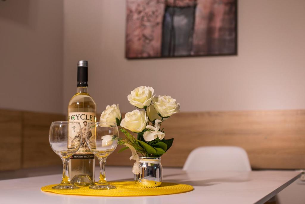 Old Town Apartment في بلوفديف: زجاجة من النبيذ و إناء من الزهور على طاولة