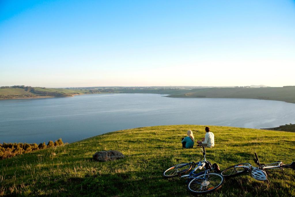 two people sitting on top of a hill with bikes at Lakes and Craters Holiday Park in Camperdown