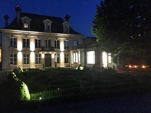 a large white house with lights on it at night at La Maison Dans le Parc in Saint-Dizier