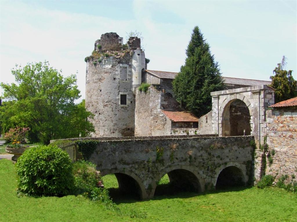 un viejo castillo con un puente en un campo en Château de la Galissonnière en Le Pallet