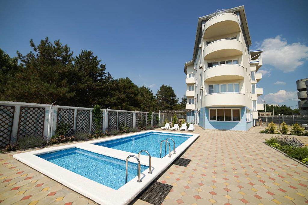 uma piscina em frente a um edifício em Robinzon Hotel em Anapa