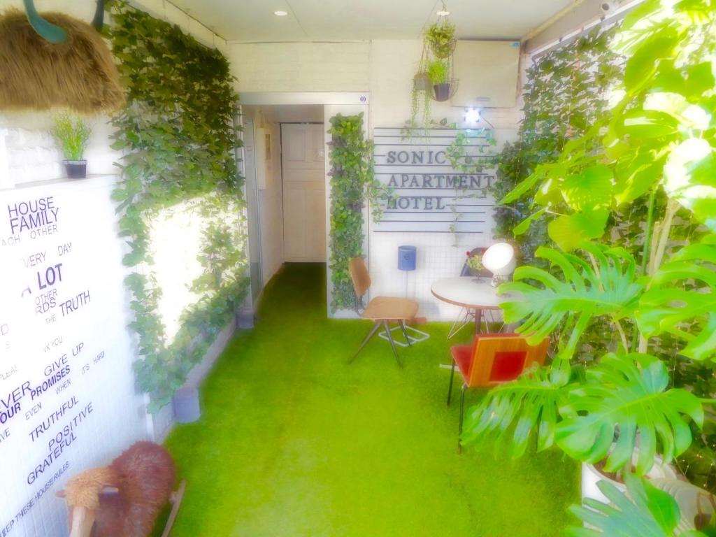 SONIC APARTMENT HOTEL في دازايفو: غرفة بها عشب أخضر وطاولة وكراسي