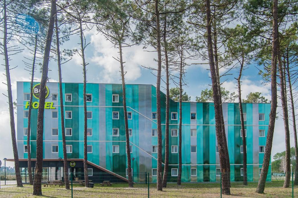 a blue building with trees in front of it at B&B HOTEL Arcachon Gujan-Mestras in Gujan-Mestras