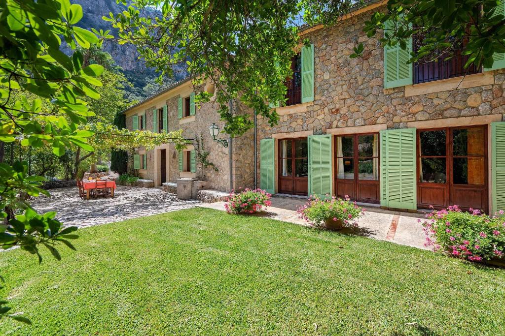a stone house with green shutters and a yard at Villa Matge in Valldemossa