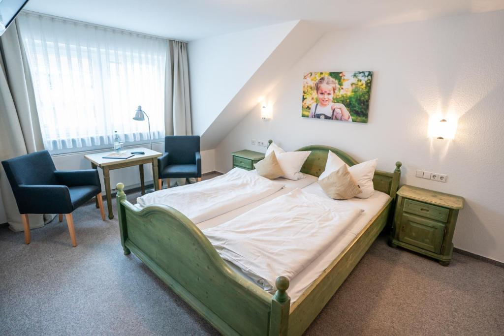 una camera con un grande letto e due sedie di Hotel-Gasthof zur Linde a Langenau