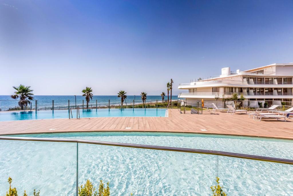 una piscina con el océano en el fondo en The Edge Front Line Beach Luxury and Spa en Estepona