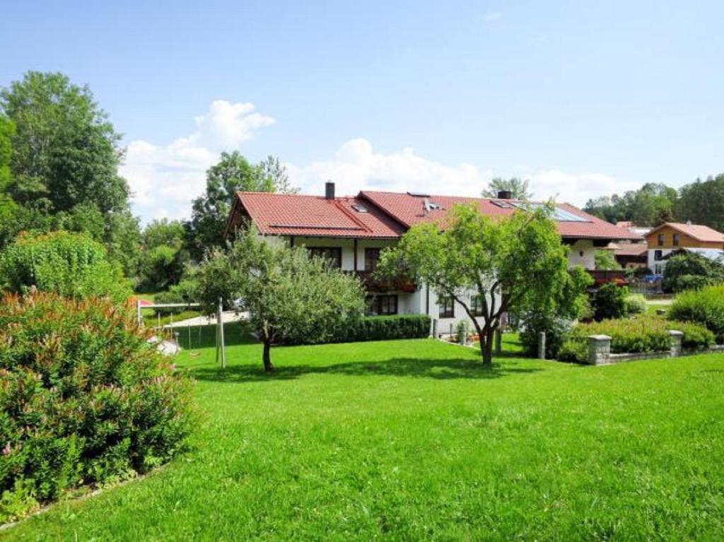 una casa con un patio con césped verde y árboles en Ferienwohnungen und Ferienhaus Kronner, en Zachenberg